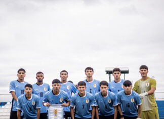 Consumado avance al Mundial ¡Cante, Uruguay!: 3-0 Uruguayan men’s soccer team posing for a group photo on the field in light blue jerseys, goalkeeper in yellow, in front of a news-style banner.