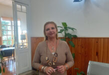 Falsas amenazas de tiroteo en liceos de Salto: Autoridades refuerzan medidas de seguridad y mantienen puertas abiertas Woman in a beige sweater stands indoors in front of a green news banner about false threats in high schools.